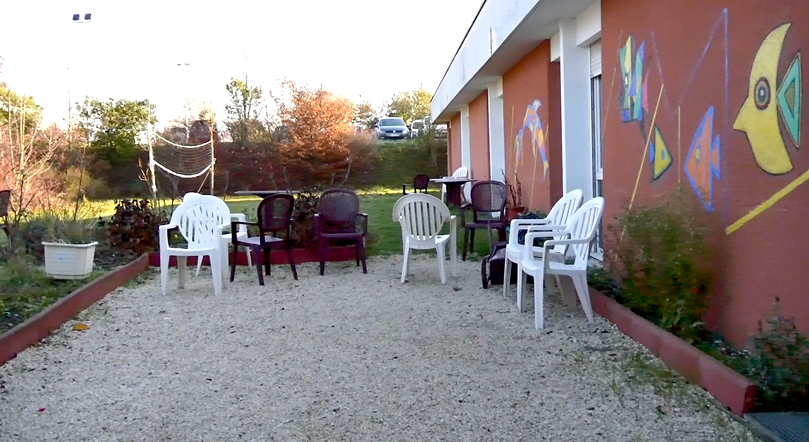 une court avec des chaises et un mur tagué 