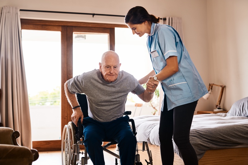 une infirmière qui aide une personne âgée en fauteuil roulant 