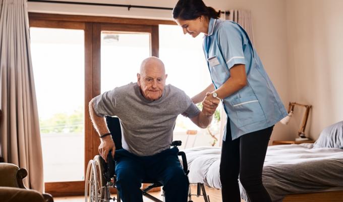 une infirmière qui aide une personne âgée en fauteuil roulant