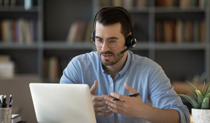 Un homme avec un casque face à son ordinateur en réunion 