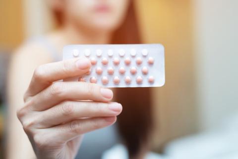 une main de femme qui tient une plaquette de pilule 