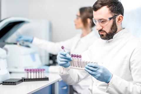 Un technicien de laboratoire qui porte des lunettes de protection tient des flacons 