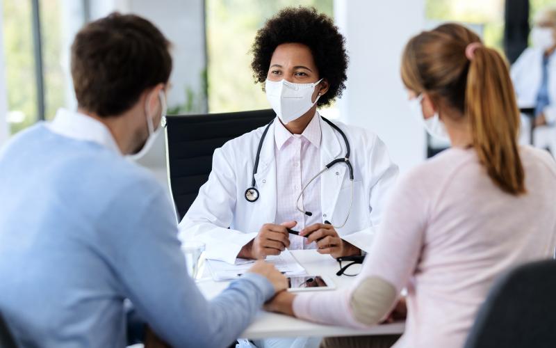 Une médecin en consultation avec un couple pour un PMA 