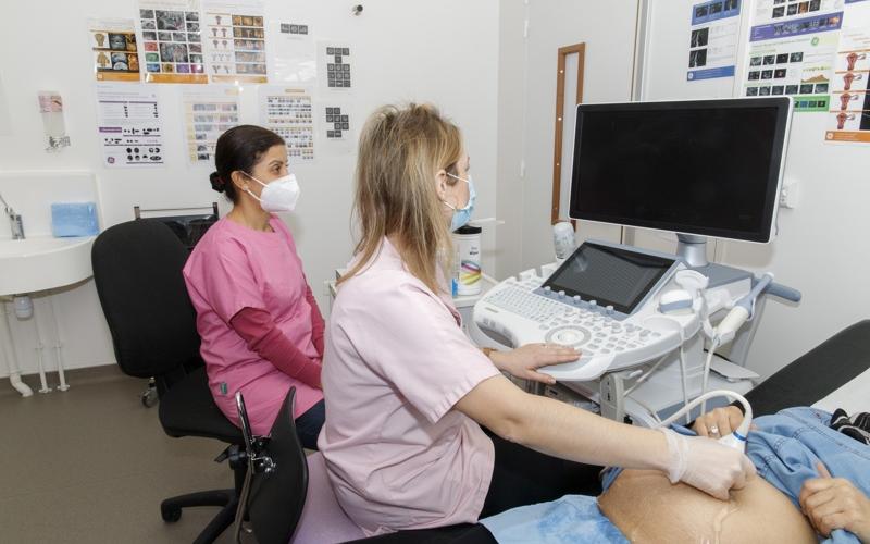 un gynécologue avec un infirmière qui pratiquent une échographie sur une femme enceinte 