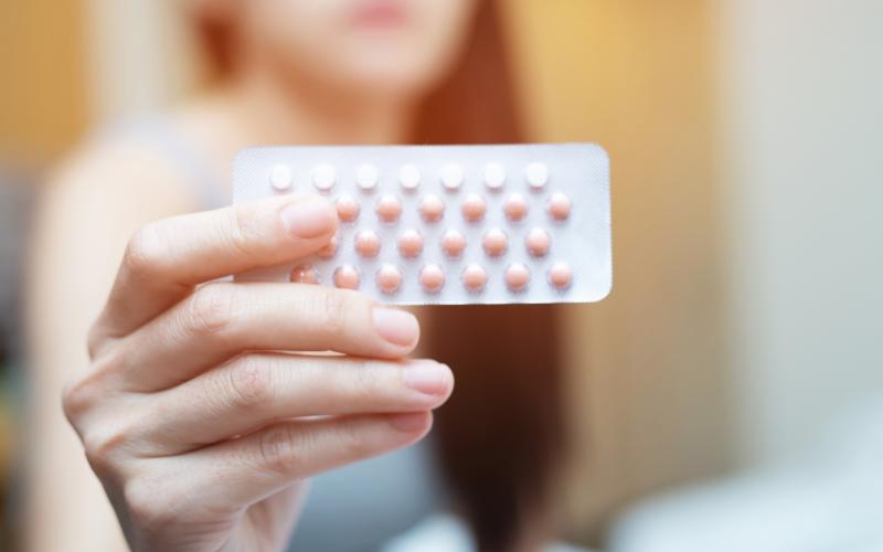 une main de femme qui tient une plaquette de pilule 