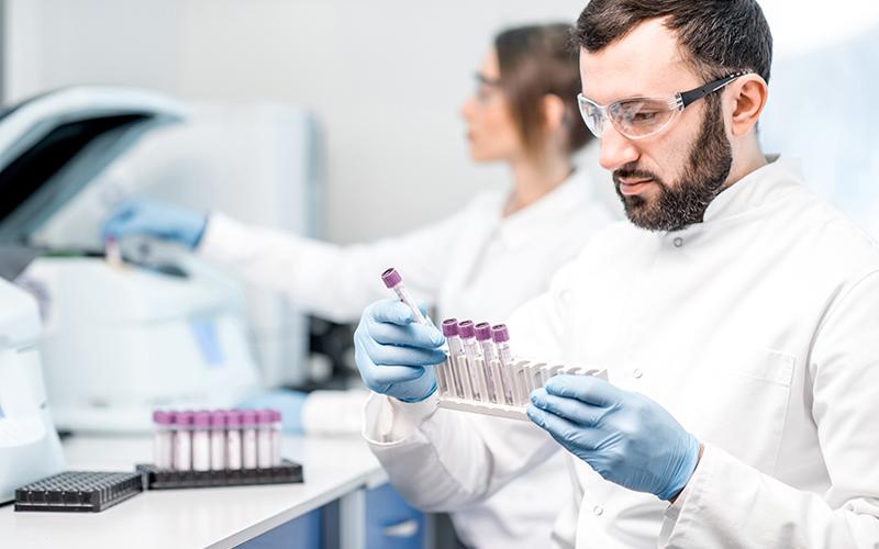Un technicien de laboratoire qui porte des lunettes de protection tient des flacons 