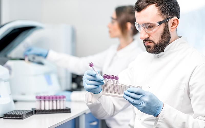 Un technicien de laboratoire qui porte des lunettes de protection tient des flacons 