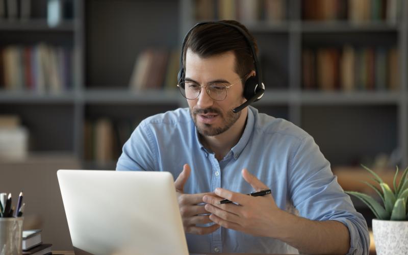 Un homme avec un casque face à son ordinateur en réunion 